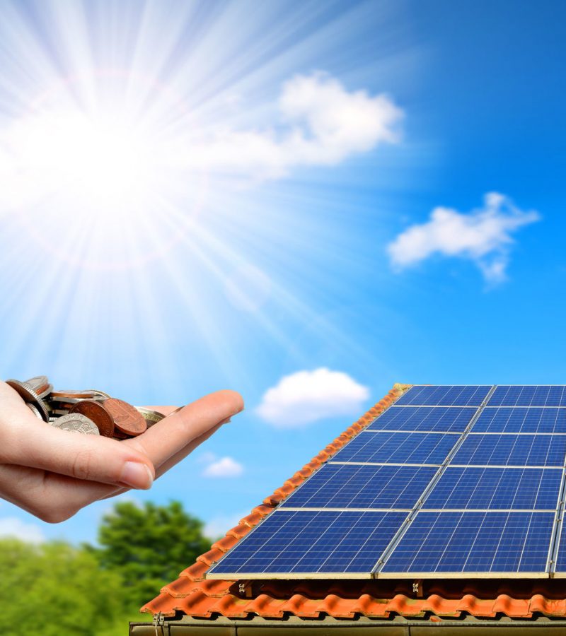 88570932 - solar panel on the roof of the house and coins in hand. the concept of money saving and clean energy.